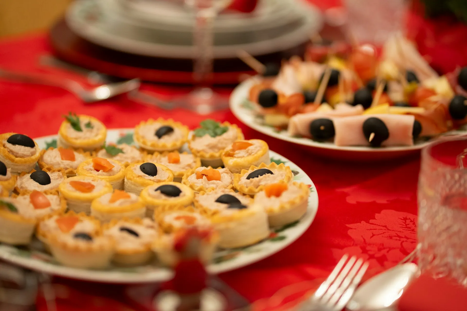 Gefüllte Blätterteigtörtchen mit Oliven als Fingerfood auf einer roten Tischdecke