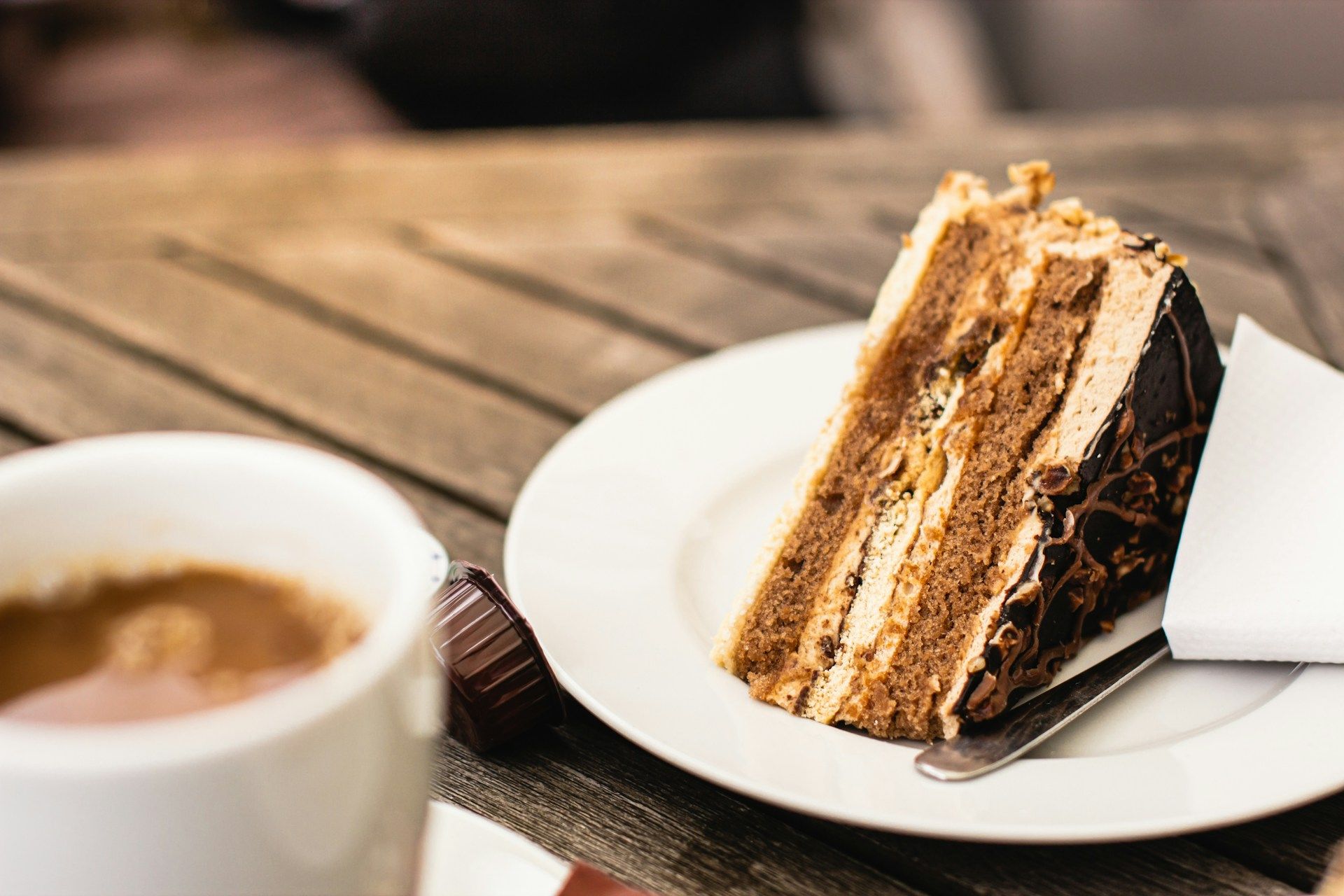 Ein Stück Schichttorte und eine Tasse Kaffee auf einem Holztisch