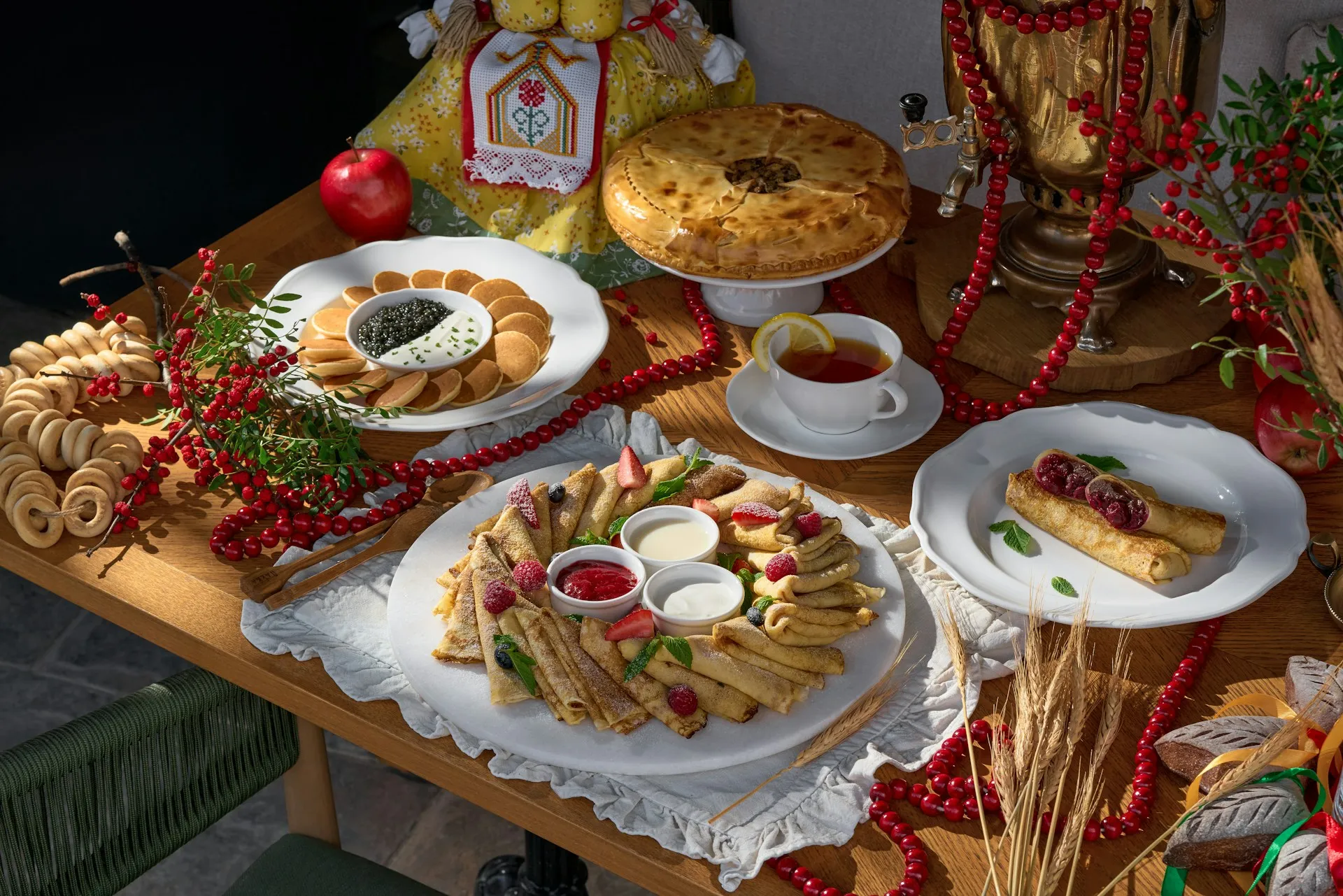 Ein festlich gedeckter Tisch mit Gebäck, gefüllten Pfannkuchen, Dips und roten Beeren