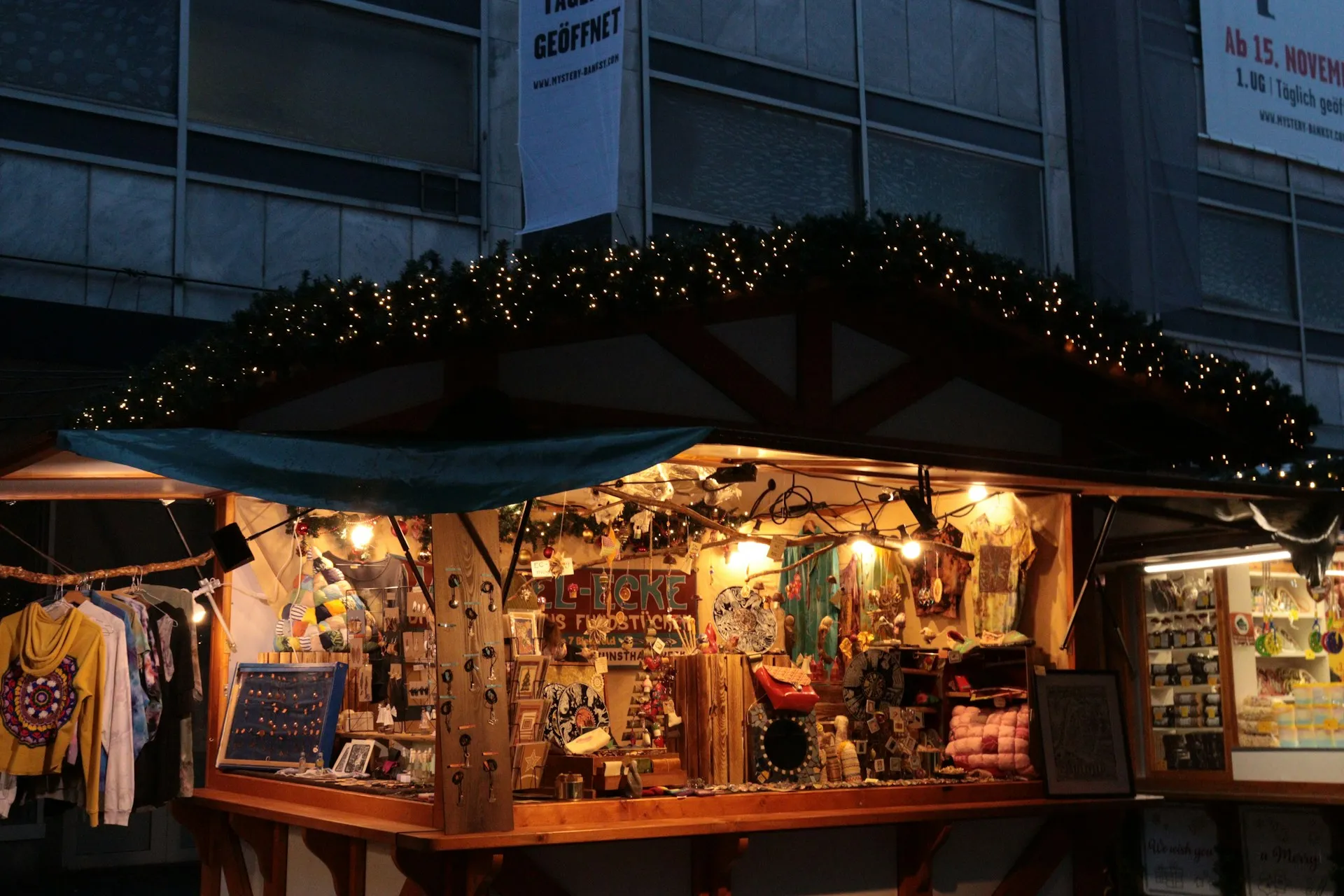 Ein beleuchteter Weihnachtsmarktstand mit Tannengirlande in der Abenddämmerung